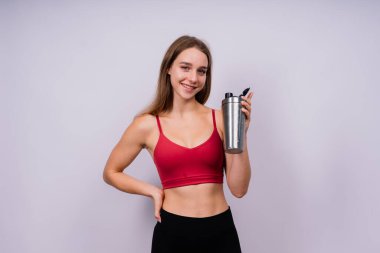 Spor şişesinden tatlı su içen spor düşkünü bir kadının yakından görüntüsü.