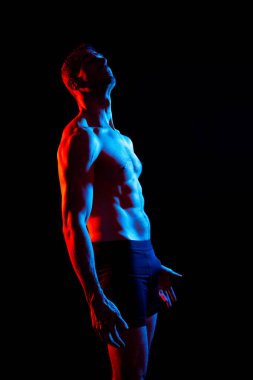 Stüdyoda poz veren kaslı bir adam resmi, koyu beyaz arka plan.