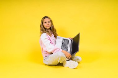 Dizüstü bilgisayarı olan genç bir kız stüdyoda oturuyor.