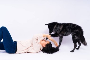 Sıradan giyinen mutlu esmer kadın. Evcil köpeğine sarılıyor. Stüdyo geçmişi var..