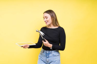 Tabletli ve çekiçli kadın, Stüdyo ışıkları sarı arka plan izole, kopyalama alanı