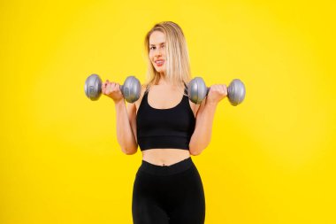 Dambıllarla spor yapan mükemmel bir bayan. Spor giyimli kadın fotoğrafı, stüdyo fotoğrafı.