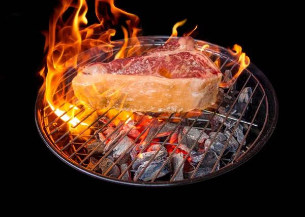 烤肉时 烤肉上烤着一块烤着的T形骨牛排 烤着的炭火背面是黑色的 — 图库照片