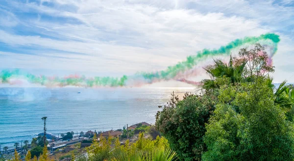 Coastal scenery with colorful fume trails of an air show seen in Liguria, Italy