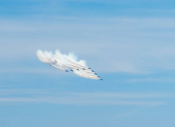 Air show of the Frecce Tricolori aerobatic team of the Italian Air Force with smoke trails in front of mostly clear sky