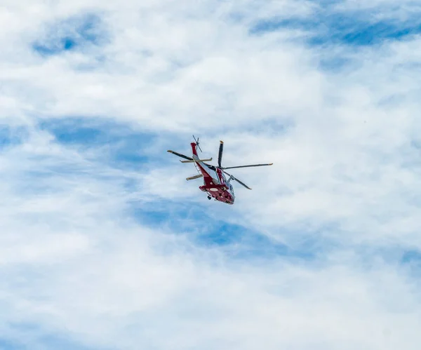 在部分云雾笼罩的天空前的一架飞行直升机的低角度镜头 — 图库照片
