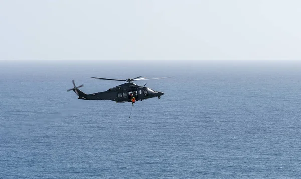 直升机在空旷的海面上飞行 而一个人正在滑行 — 图库照片