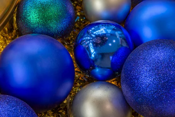 Blue and silver colored christmas baubles and christmas tree lights in golden ambiance