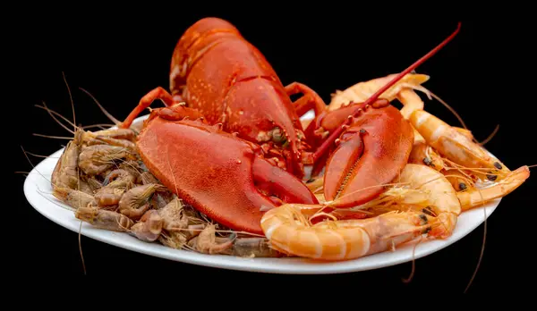 stock image Closeup shot of a cooked lobster and some other crayfish on a plate in black back