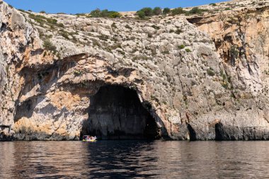 Blue Grotto - Qrendi, Malta 'da bir turist teknesi bir mağaraya giriyor.