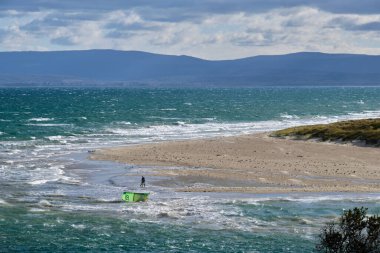 Dalgalı deniz ve Sandpiper Sahili 'nde yalnız bir uçurtmacı Coles Körfezi, Tazmanya, Avustralya
