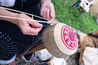 Elderly person's hands busy building a basket by weaving branches. The art of wicker weaving