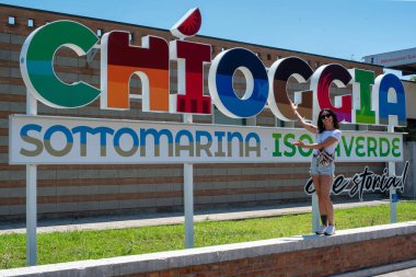 15 / 06 / 23 - Chioggia, İtalya: Venedik yakınlarındaki Sottomarina plajlarında turistleri karşılayan çok renkli tabela, şu sözlerle karşılanıyor: Chioggia, Sottomarina, Isolaverde, ne tarih! Kız sunuyor.