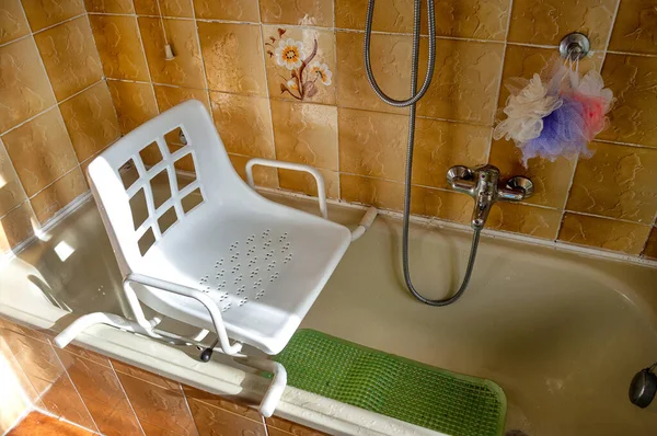 욕조에 위치한 의자는 장애인과 욕조에 들어가기 어려움을 노인들에 사용됩니다 스톡 사진