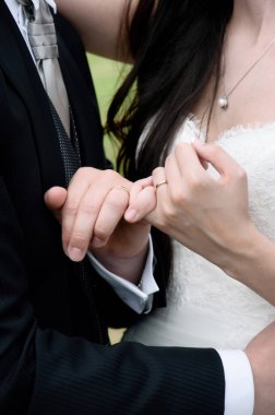 Yeni evli çiftin elleri birbirine dolanmış ve alyansları belirgin bir şekilde sergileniyor.