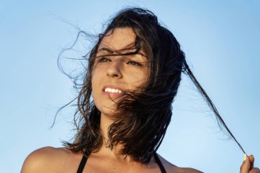 Gözleri ufukta kaybolmuş, ıslak saçlarına tek eliyle dokunan güzel bir kızın yüzü.