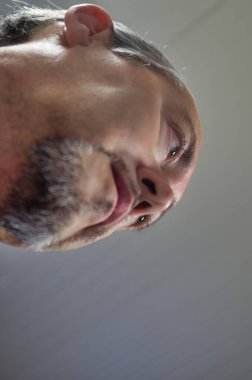 50 yaşında, beyaz saçlı ve sakallı bir adamın yakın plan fotoğrafı.