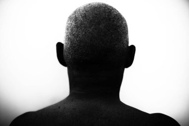 Close-up of the back of a shaved man's head in dim light clipart