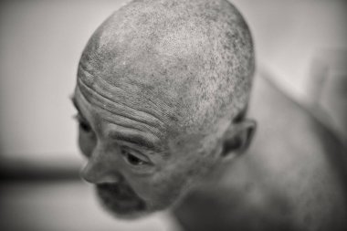 Kafası kazınmış ve rahatsız edici bakışları olan bir adam, zihinsel sıkıntıyı işaret ediyor.