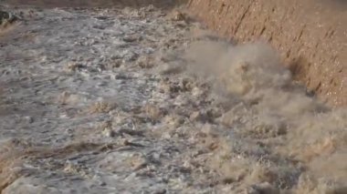 Ağır çekimde, nehir yatağında güçlü bir su ve çamur akışı.