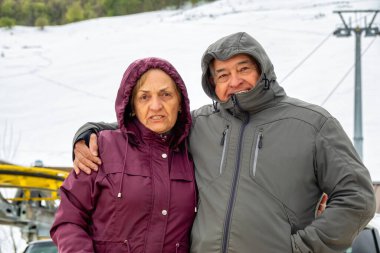 Elderly couple  wearing winter jackets to protect themselves from the mountain cold in winter clipart