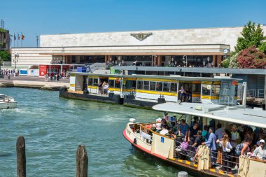 2 Temmuz 2025 Venedik İtalya Venezuela Santa Lucia tren istasyonu, İtalya, güneşli bir yaz gününde Büyük Kanal 'ın karşısından izlendi. Önplanda, kalabalık bir buharlı otobüs (su otobüsü) Ferrovia ACTV durağına yaklaşır.