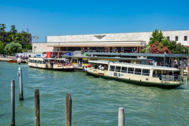 2 Temmuz 2025 Venedik, Venedik Santa Lucia tren istasyonu, Büyük Kanal 'dan ele geçirildi. Ön planda, rıhtımdaki ACTV rıhtımı tarafından işletilen kalabalık buharlı su otobüsleri, lagün şehrindeki toplu su taşımacılığının önemini vurguluyor..