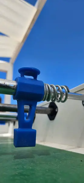 stock image Table football, A close-up of a blue foosball player figure attached to a metal rod, with a clear blue sky in the background