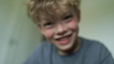 Yatakta gülümseyen 6 yaşındaki bir çocuğun yakın plan portresi. Yüksek kalite 4K görüntü. Mutlu şirin çocuk gülümseyip yatağında oynaşıyor. Yakından bir gülümseme, dişleri ve baklavaları..