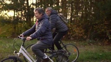 Sonbaharda bir sonbahar günü bisiklet süren birkaç emekli. 60 yaşın üstündeki insanlar, gençlik çağında. Yüksek kaliteli FullHD görüntüler
