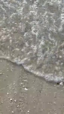 Kumlu bir sahil manzarası. Dalgalar yavaşça kumu kaplıyor. Çeşitli sosyal medya paylaşımları için arka plan olarak mükemmel.