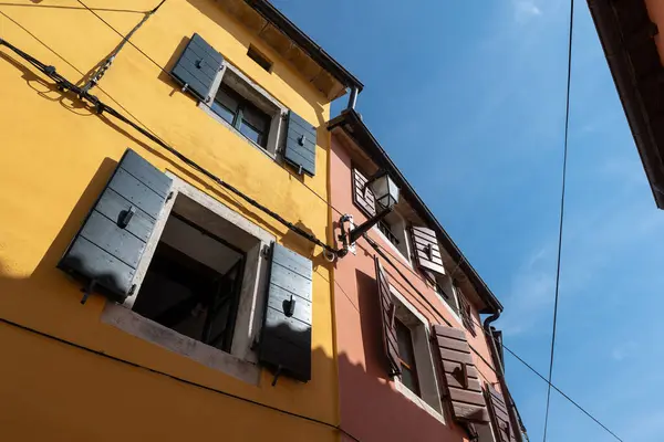 Kahverengi kepenkleri ve renkli taş evi olan pencereleri aç