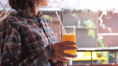 Sabah kafedeki terasta taze portakal suyu içen bir kadın.