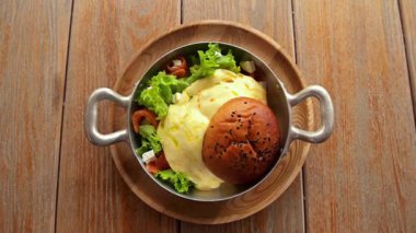 Yumurta, mevsim tohumları, ekmek ve ahşap masada taze salata ile nefis bir kahvaltı.