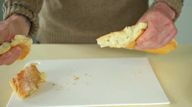 Adam Fransız ekmeğini elleriyle parçalara ayırıyor.