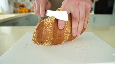 Adam altın çıtırtı ve susam tohumlarıyla taze ekmek kesiyor.