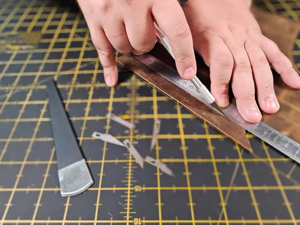 Erkeklerin ellerini yakın çekim. Eller bir parça deri kesti. Yumruğu yumrukla. Deri üzerinde özel aletlerle çalışmak. Yakın plan iş.