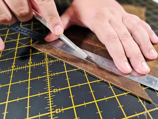 Erkeklerin ellerini yakın çekim. Eller bir parça deri kesti. Yumruğu yumrukla. Deri üzerinde özel aletlerle çalışmak. Yakın plan iş.