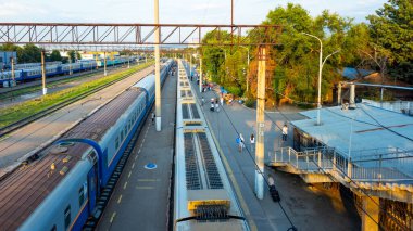 İstasyon önlüğü. Tren geldi. Yolcular geliyor. Platformdaki insanlar. Bavullu insanlar var. Köprü merdivenleri. Köprü.