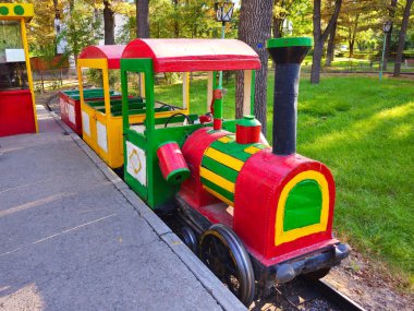 Children's attraction, old little train in an amusement park. Non-working children's attraction in the park. clipart