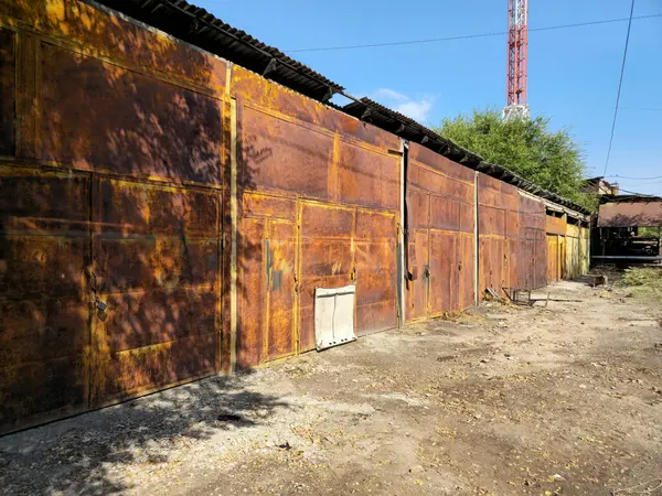 Paslı garajlar, depolar, terk edilmiş binalar. Köşe perspektifi. Eski bir binanın paslı kapıları..