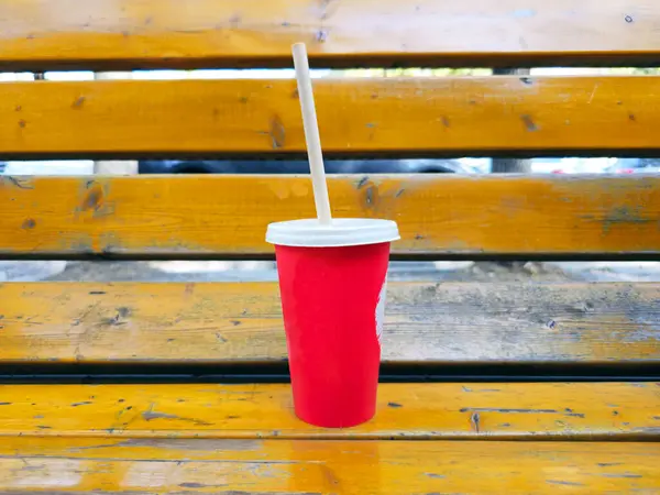 Kağıt bardak bankta. Kırmızı bir kağıt bardak dışarıda, bir bankta..