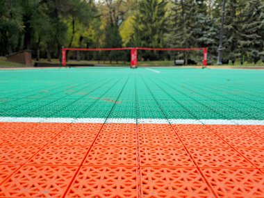 An orange and green tennis court installed in the park, temporarily for the tournament. clipart