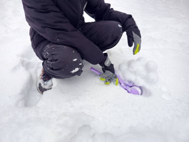 Çocuk oynamak için kartopu yapıyor. Karlı kış. Bir sürü kar, kartopu, kartopu yapmak için oyuncak.