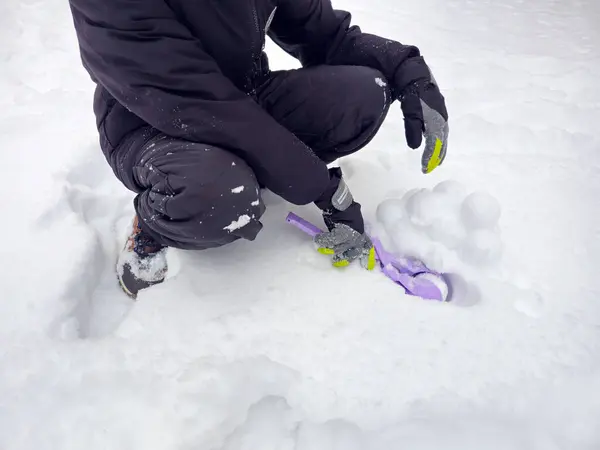 Çocuk oynamak için kartopu yapıyor. Karlı kış. Bir sürü kar, kartopu, kartopu yapmak için oyuncak.