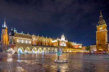 Cracow, Poland, 23 July 2022: Krakow city in the evening in Poland, Main Square in the Old Town, illuminated St. Mary Church and Cloth Hall (Sukiennice).
