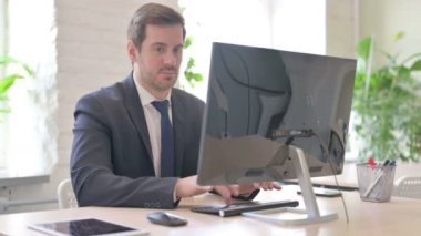 Bilgisayar üzerinde çalışan meşgul genç yetişkin iş adamı