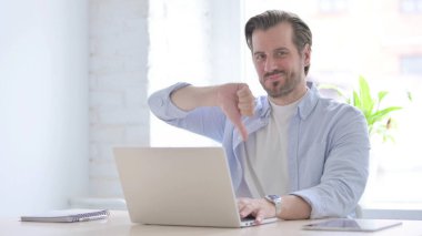Mature Man Showing Thumbs Down While using Laptop
