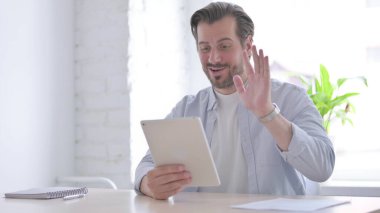 Mature Man Doing Video Call on Tablet in Office