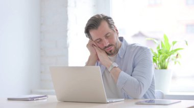 Mature Man with Laptop Taking Nap in Office